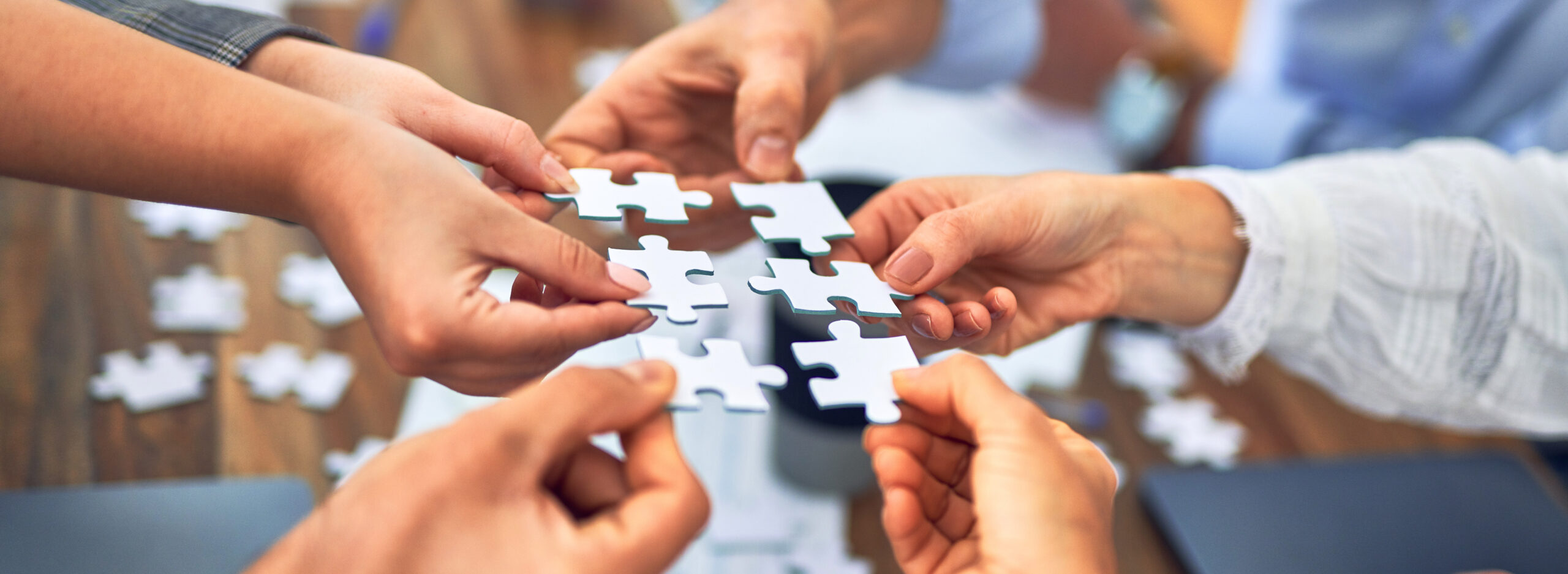 Group of business workers with hands together connecting pieces of puzzle at the office